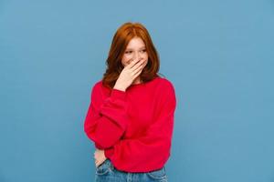 Young ginger-haired woman laughing and covering her mouth photo
