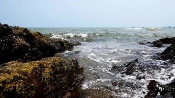 close-up de zee golven zachtjes tegen de rotsen. op een zonnige dag waait de wind zachtjes.