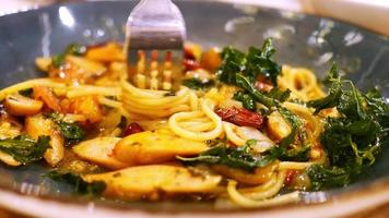 espaguetis con salchicha y albahaca. en plato negro con tenedor girando hebras de espagueti. video