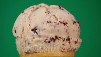 Vanilla chocolate chip ice cream on  cone. The texture of the ice cream and chocolate flakes. on green background. video