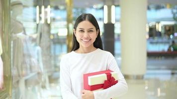 mujer sosteniendo una caja de regalo en el centro comercial, acción de gracias y concepto de navidad.
