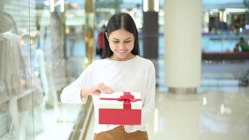 donna che tiene una confezione regalo nel centro commerciale, il ringraziamento e il concetto di natale. video