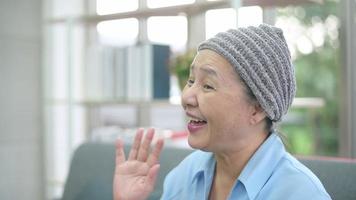 mujer paciente con cáncer con pañuelo en la cabeza haciendo videollamadas en las redes sociales con familiares y amigos en el hospital. video