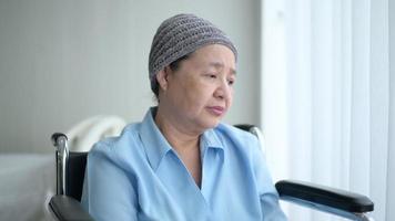 Depressed and hopeless Asian cancer patient woman wearing head scarf in hospital. video