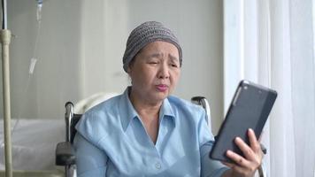 donna malata di cancro che indossa una sciarpa per la testa che effettua una videochiamata sul social network con la famiglia e gli amici in ospedale. video