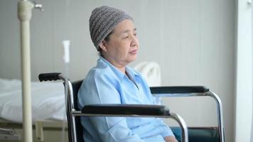 Depressed and hopeless Asian cancer patient woman wearing head scarf in hospital. video