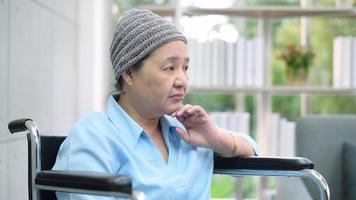 Depressed and hopeless Asian cancer patient woman wearing head scarf in hospital.