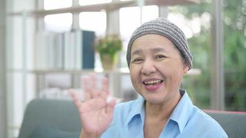 mulher paciente com câncer usando lenço na cabeça fazendo videochamada na rede social com familiares e amigos no hospital.