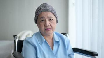 Depressed and hopeless Asian cancer patient woman wearing head scarf in hospital.