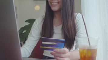 A young beautiful woman is using credit card for shopping online  in coffee shop video