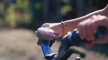 närbild av ett barns hand som ringer en cykelklocka på ett cykelstyre i en park. video