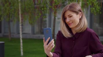 Frau chattet und gestikuliert während eines Online-Videoanrufs aus dem Stadtpark. video