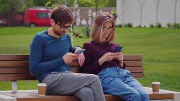 dos amigos que usan teléfonos inteligentes en el parque al aire libre.