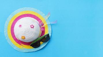 concepto de fondo de viaje - artículos accesorios de viaje de verano con gafas de sol y sombrero colorido para viajeros sobre fondo azul foto