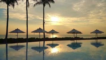 Sonnenschirm mit Bettpool rund um den Pool mit Ozean-Meer-Hintergrund - Urlaubs- und Urlaubskonzept video