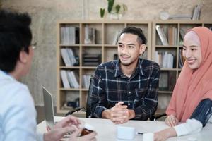 People medical insurance clinic service. Young Muslim couple discussing and consulting with a professional Asian male doctor about his wife's health who is a beautiful woman wears a hijab in office. photo