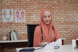 Portrait of a beautiful female doctor, beautiful Muslim in uniform with a stethoscope, smiling and looking at the camera in hospital's clinic. One person who has expertise in professional treatment. photo