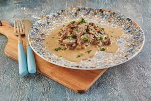 Stroganoff de ternera en un plato y utensilios para comer. cocina gourmet francesa foto