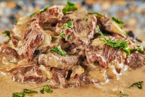 Stroganoff de ternera en un plato y utensilios para comer. cocina gourmet francesa foto