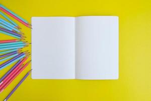 Blank notebook, a pencil, and space are on top of a yellow office desk table. Flat lay, top view education concept photo