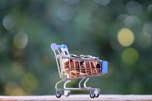 Coin  in trolley on green bokeh background and business or finance saving money