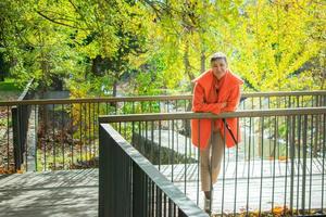woman in orange coat leaning against metal railing
