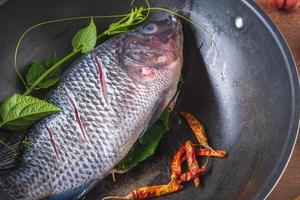 Fresh fish in a pan and spices to cook photo