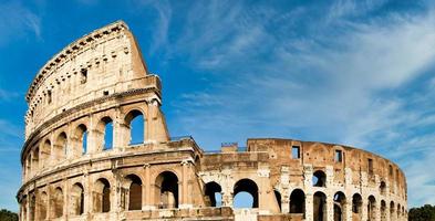 Roma, Italia. Arquitectura de arcos del exterior del Coliseo con fondo de cielo azul y nubes. foto