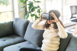 Latin woman using a virtual reality headset on sofa photo