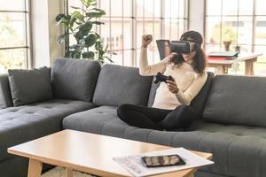 Mujer latina con un casco de realidad virtual en el sofá foto