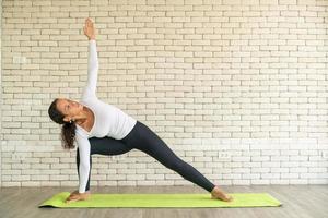 Latin woman practicing yoga on mat photo