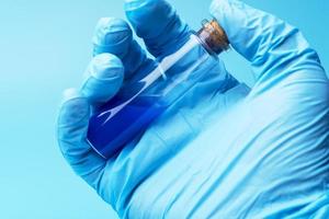 primer plano de tubo de vidrio con líquido azul en la mano del científico durante la prueba médica foto