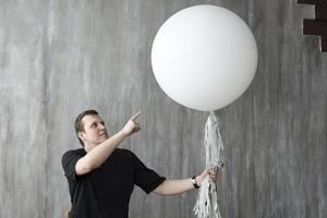 un hombre sosteniendo una pelota inflable sobre un fondo gris. foto