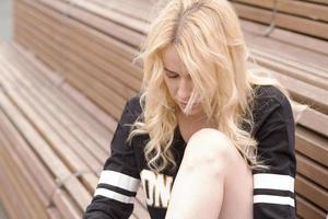 The girl sits on the bench at the football field with the ball. photo