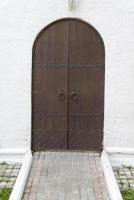 An old, arched wooden door with iron hinges. photo