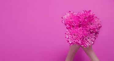 composición de flores de verano con mano de niña aislada sobre fondo rosa. día de la madre y la mujer. concepto de vacaciones de san valentín. vista superior y espacio de copia. banner y maqueta. temporada de flores foto