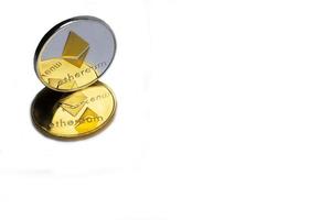 Two real coins of silver and golden cryptocurrency Ethereum, isolated on white background photo