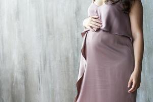 The abdomen of a pregnant woman on gray background.