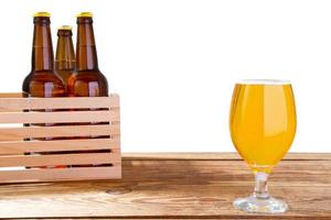 glass of beer and bottles with no logo on wooden table isolated copy space, glass bottle photo