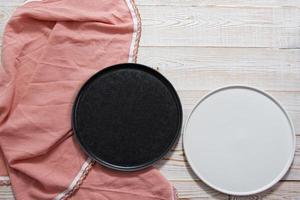 black and white empty plate mock up top view on wooden table, table cloth napkin top view photo