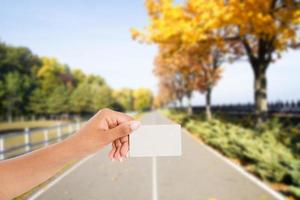 black hand hold business card on blurred background asphalt road to horizon in park photo