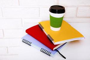 Stylish macro cup of coffee and notebook in office. Selective focus and copy space. Brick wall and workplace business concept. photo