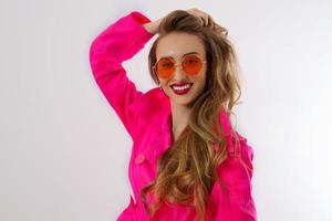 Happy, shock, excited woman face closeup. Girl in bright pink autumn clothes, red sunglasses isolated on white background, copy space. Beautiful female surprised, cheerful. Fun funny model screaming photo