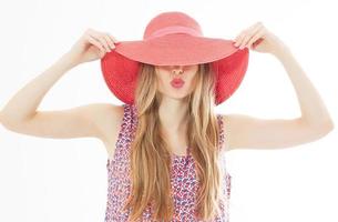 Portrait of young stylish kissing girl model in colour casual summer clothes in red pink hat with natural makeup and long blond hair isolated on whitebackground. Hide eyes. photo