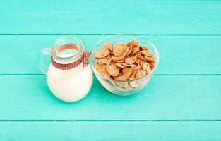 Food concept. Oat flakes and jug of milk on blue wooden background. Top view and copy space. Mock up
