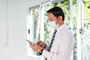 a business man standing by the window using a mobile phone photo