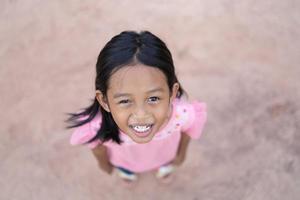 A portrait of an Asian little girl standing on the ground. photo