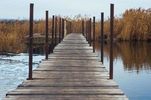 Wet, wooden bridge over the river. Makeshift river crossing photo