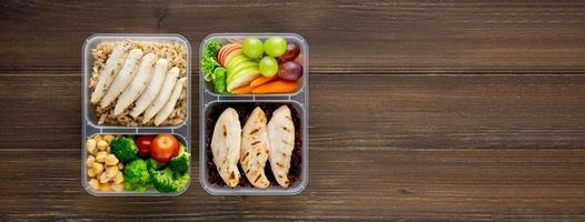 Clean healthy low fat food in two takeaway meal box sets on wood banner background top view with copy space photo
