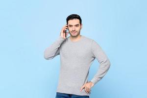 Portrait of handsosme Caucasian man calling on mobile phone in isolated light blue studio bakground photo